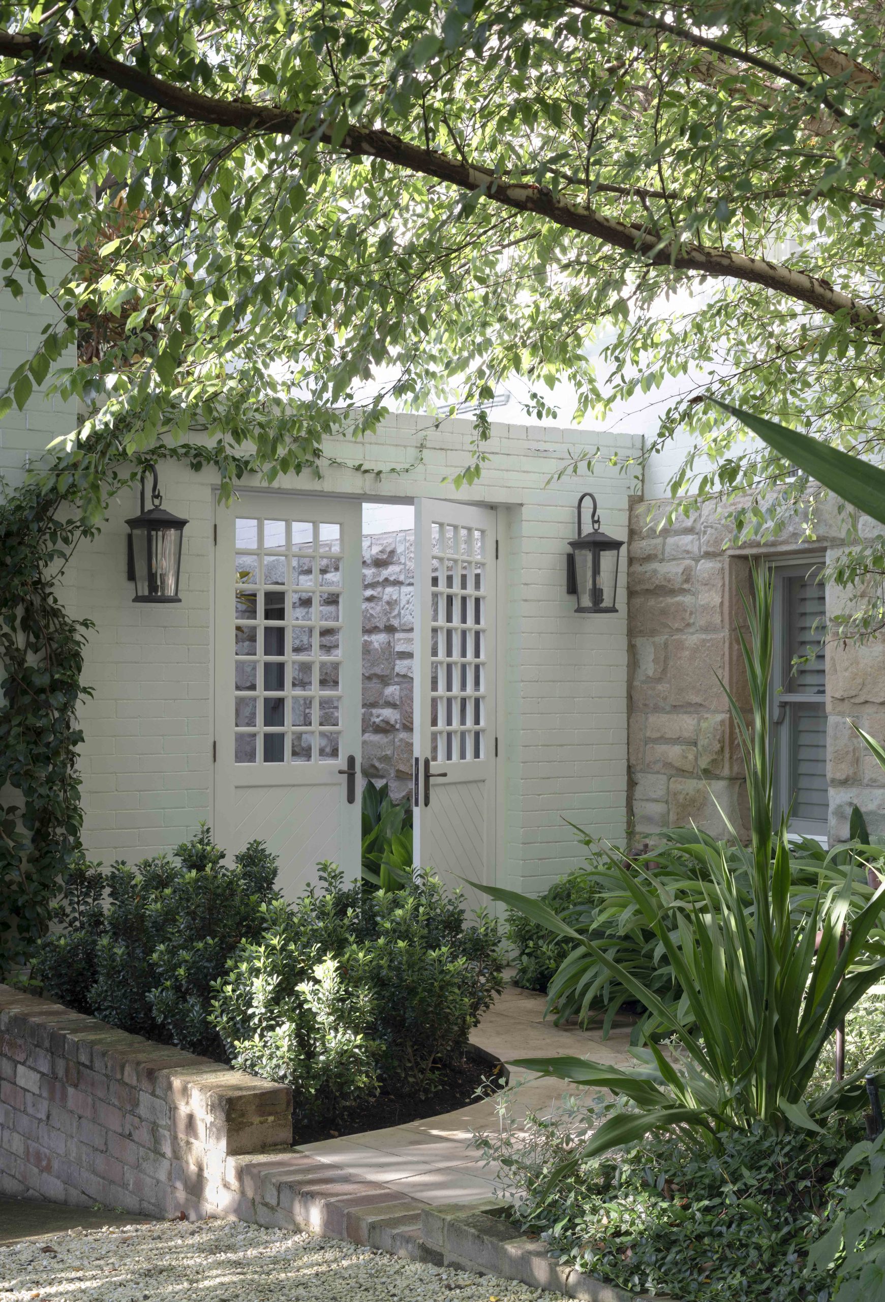 A functional yet beautiful glass and timber gate frames views to a layered garden bed. Photo by Wyer & Co. | Landscape Design on January 09, 2023. Decorative gate is a defining feature of this federation-style home is Sydney’s Mosman.