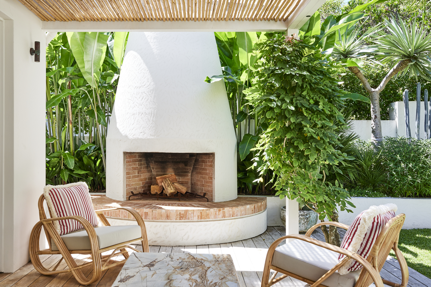 An outdoor fireplace ensures the garden is used year-round. The property is hugged by greenery. Mediterranean-style garden feature handbuilt circular fireplace and outdoor entertaining area. Mediterranean-style garden