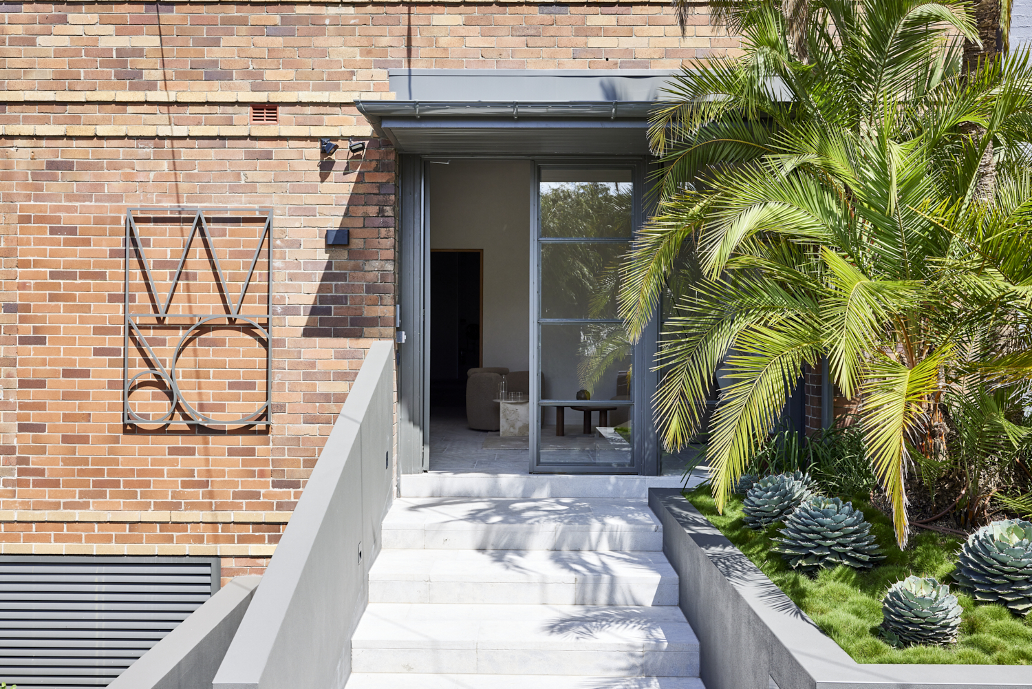 Wyer and Co. head office boardered by lush garden beds, dense greenery and phoenix palms.