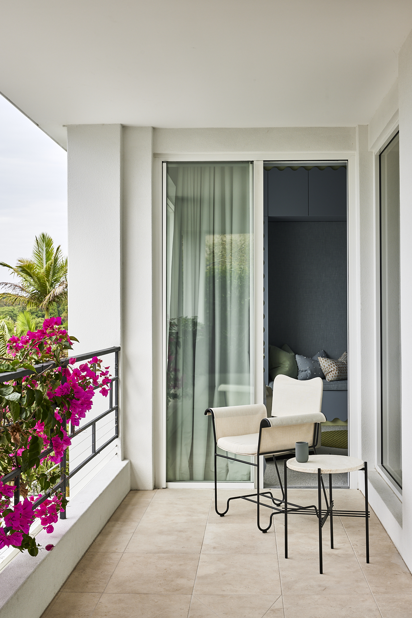 The balcony is framed in brilliant prink bougainvillea, A single seat presents the prefect place to admire the garden from above.